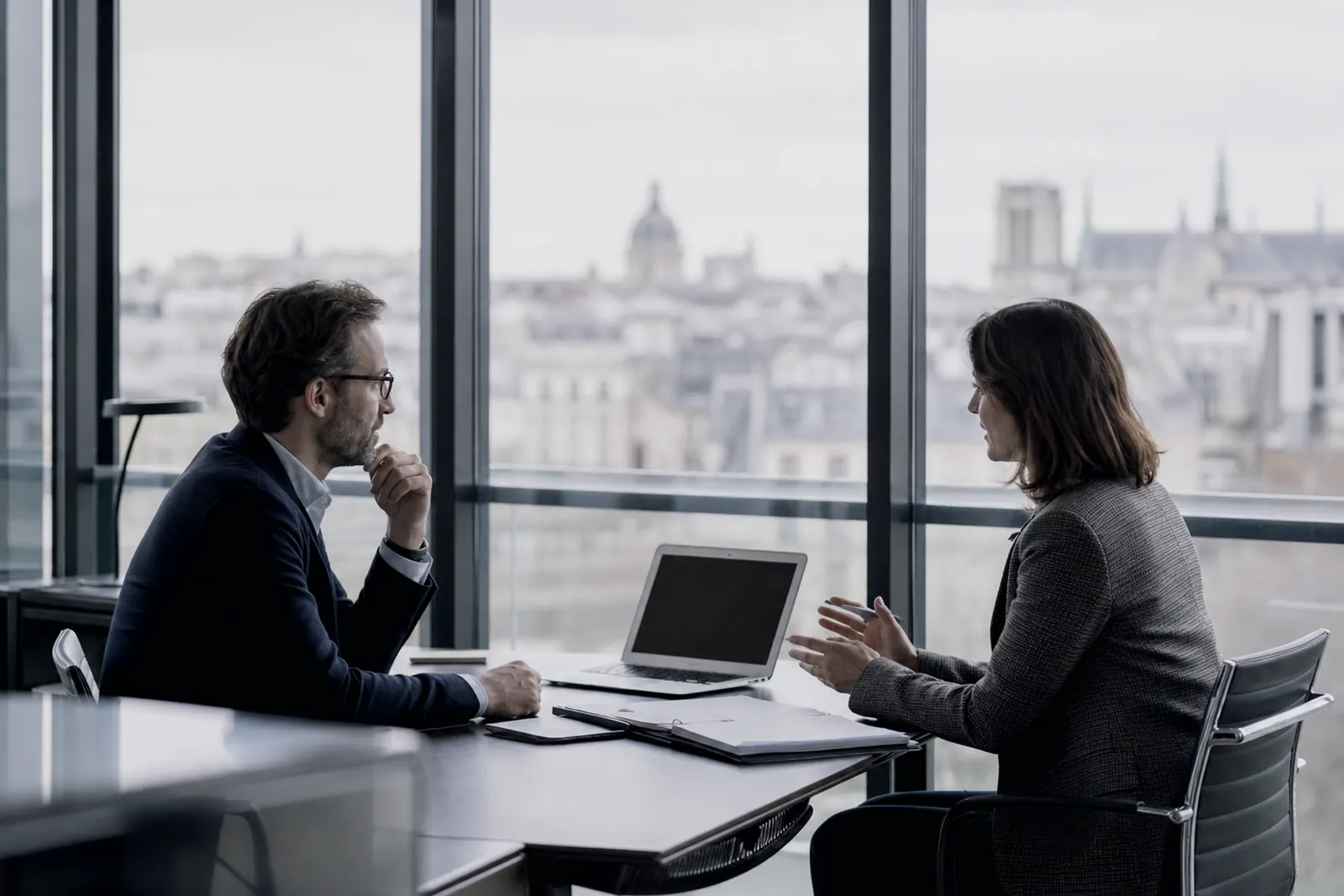 Rendez-vous professionnel dans un bureau vitré, deux personnes assises face à face.